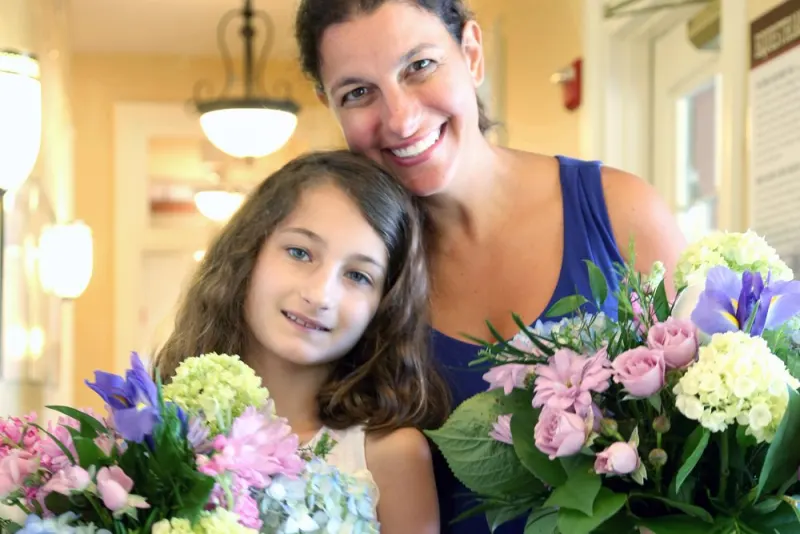 A mother and daughter holding flower arrangements